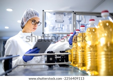 Food inspector or technologist taking good care of bottled vegetable oil inside bottling plant. Royalty-Free Stock Photo #2256409113