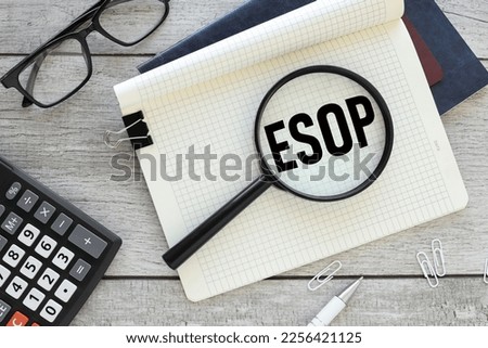 ESOP, text on magnifier glass on notepad. view from above. calculator near notepad.. esop - short for Employee Stock Ownership Plan