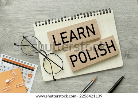 Learn Polish. text on blocks of wood. notepad and glasses are on the table. Royalty-Free Stock Photo #2256421139