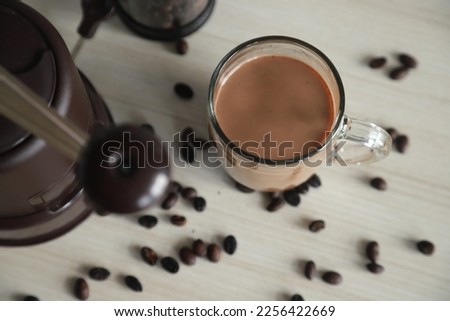 a glass of coffee, coffee beans and ground coffee beans on the table