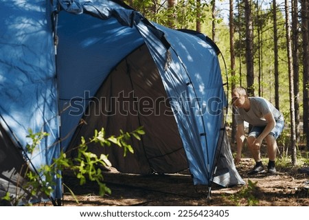 caucasian man wearing a hat putting up a tent. Family camping concept Family camping concept. High quality photo