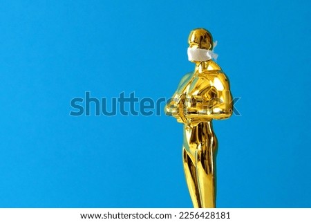 Hollywood Golden Oscar Academy award statue in mask on blue background. Success and victory concept.
