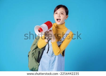 Young Asian student posing on blue background