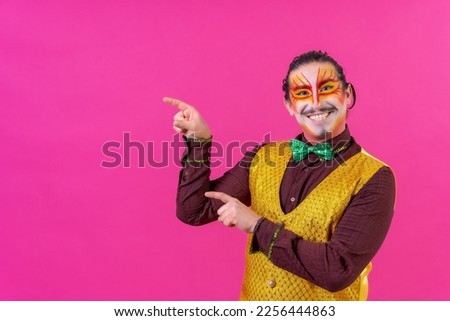Clown with white facial makeup showing an empty space from the pink background, announcing something