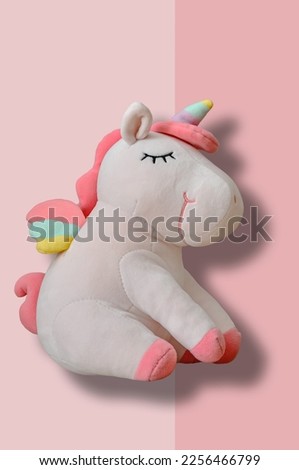 Cute soft unicorn plush toy on pink background. Close up shot