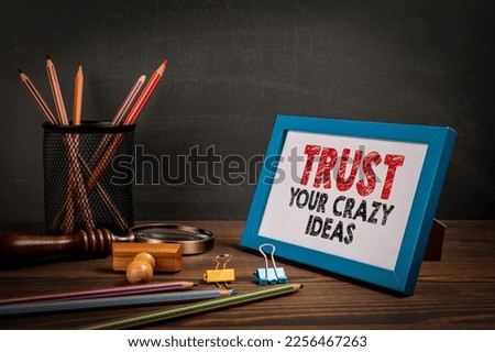 Trust Your Crazy Ideas. Motivational quote. Picture frame on the office table