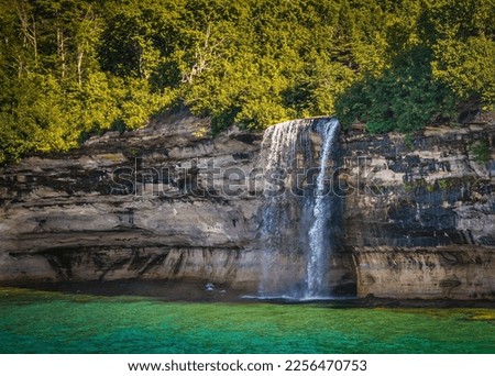Tall Bridalveil waterfall flows over Lake shore cliff