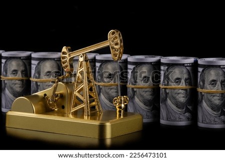 
Gold oil pump model and rolled up 100 american dollar bills