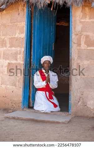 young african woman in church uniform in the yard of her village
