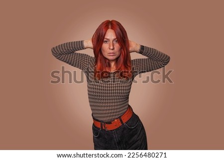 Red-haired girl withfreckles ona fleshcolredbackground. Studio photo. Girl with a lens. Portrait of a redhead girl with freckles