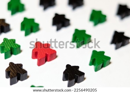 concept of individual red meeple between green and black meeples on the white background 