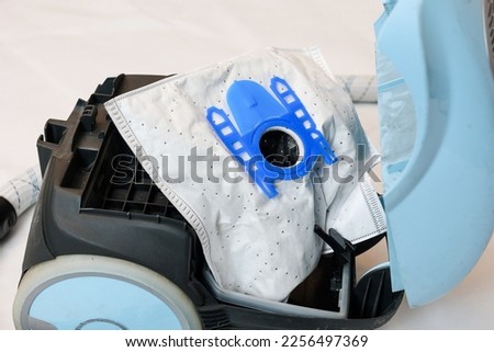 Fully dust bag in vacuum cleaner ready to be replace. Open vacuum cleaner isolated on white background, top view.  Royalty-Free Stock Photo #2256497369