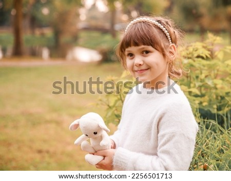 Close-up portrait of a pretty girl. The child is holding a toy Easter bunny. Spring mood. The girl smiles.
