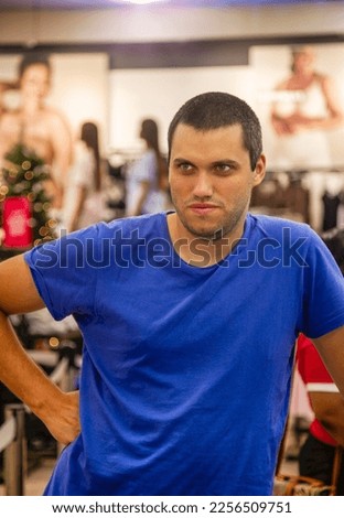 young Caucasian man with casual blue t-shirt waiting at the till checkout to pay
