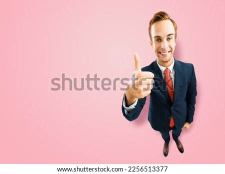 Full body businessman in black suit showing thumb up like, agree hand sign gesture on rose pink background. Comic look happy man. Cartoon style character with big head. Funny face. Copy space mockup.