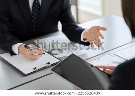 Asian business person showing and explaining a tablet Royalty-Free Stock Photo #2256528409