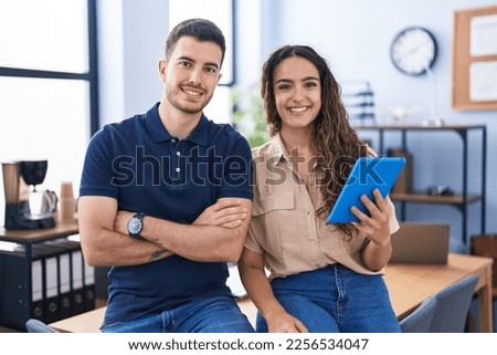 Young hispanic couple business workers using touchpad working at office Royalty-Free Stock Photo #2256534047