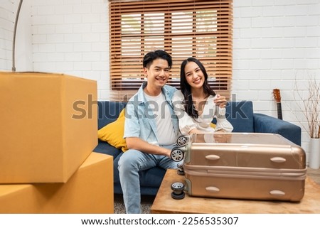 Portrait of Asian young new marriage couple move to new house together. Attractive romantic man and woman holding box parcel and suitcase with happiness and love. Family-Movehouse relocation concept.