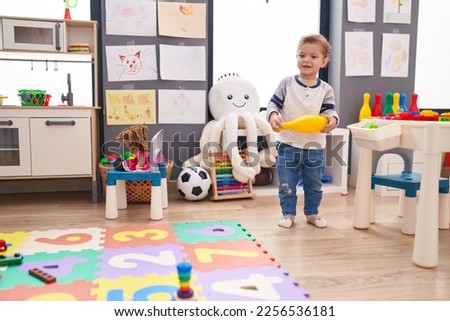 Adorable caucasian boy playing with pin bowling standing at kindergarten