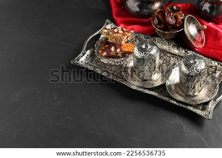 Tea, Turkish delight and date fruits served in vintage tea set on black table, space for text