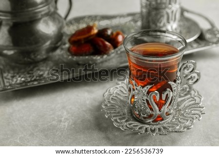 Tea and date fruits served in vintage tea set on grey table, space for text
