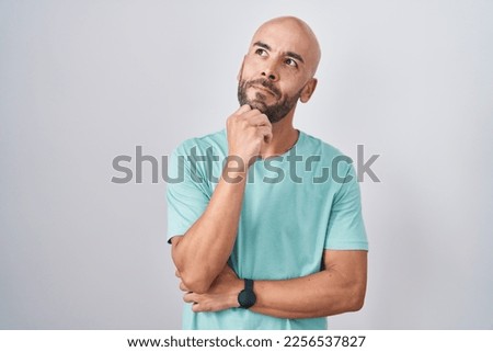 Middle age bald man standing over white background with hand on chin thinking about question, pensive expression. smiling with thoughtful face. doubt concept.  Royalty-Free Stock Photo #2256537827