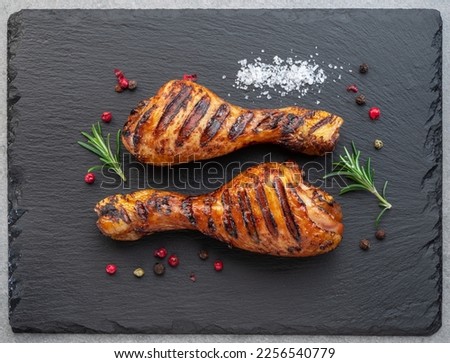 Grilled  delicious chicken legs or chicken drumsticks on black slate serving plate. Flat lay. Royalty-Free Stock Photo #2256540779