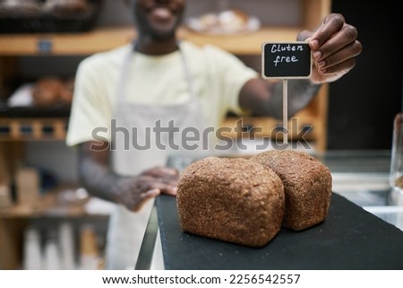 Baker putting gluten-free loafs of bread in store showcase