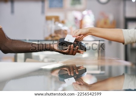 Hands of customer with credit card paying for order in bakery