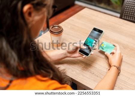detail of woman photographing credit card with mobile at table