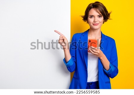Photo of cute pretty woman wear blue jacket texting gadget pointing white wall poster empty space isolated yellow color background