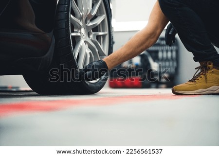 Tyre blackening. Unrecognisable man in black gloves blackening tires of car using sponge. Low angle perspective. High quality photo