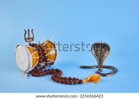 Shivaratri background with Shivas trident, Pellet Drum Damroo musical instrument ans snake . Maha Shivratri festval Royalty-Free Stock Photo #2256566423
