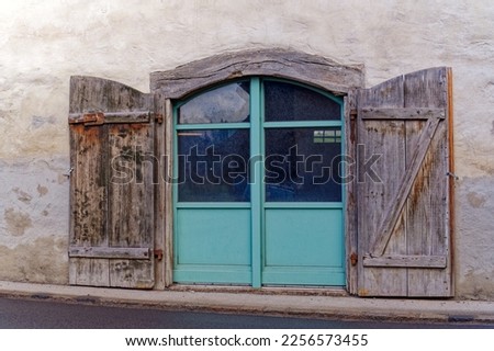 Open wooden gate with closed green metal door of historic traditional farm building at City of Zürich district Seebach on sunny winter day. Photo taken January 31st, 2023, Zurich, Switzerland.