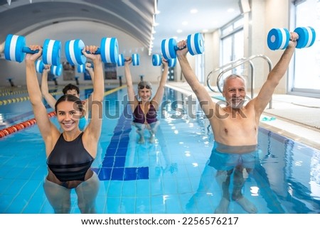 Young dark-haired coach leading a class of water aerobics Royalty-Free Stock Photo #2256576217