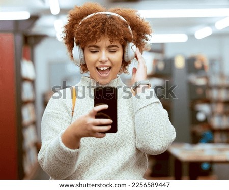 Headphones, phone and woman in the library with music, radio or podcast for study motivation. Happy, excited and female college student from Brazil listening to song, album or playlist in book store.