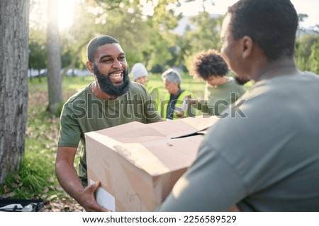 Community service, black man and giving box in park of donation, volunteering or social responsibility. Happy guy, NGO workers and helping with package outdoor of charity, support or society outreach Royalty-Free Stock Photo #2256589529