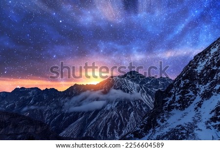 Fantasy night landscape. Beautiful snow covered mountains in the starry night with milky way galaxy.