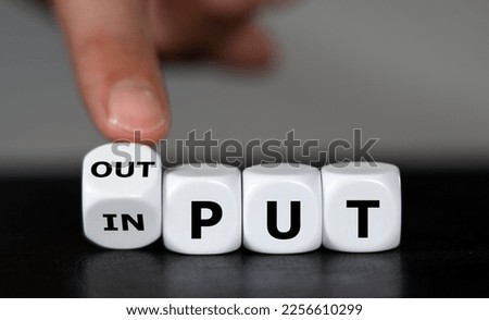 Hand turns dice and changes the word input to output.  Royalty-Free Stock Photo #2256610299