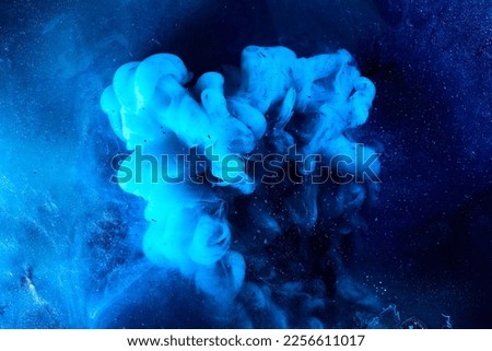 Blue abstract ocean background. Splashes and waves of paint under water, clouds of smoke in motion.