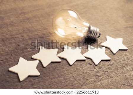 Wooden five stars with glowing light bulb, success, and idea from the excellent feedback, good performance result, customer satisfaction, and evaluation Royalty-Free Stock Photo #2256611913