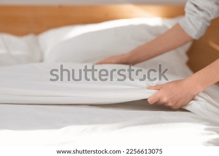 Hands of young european woman makes white bed with blanket in bedroom interior, close up, cropped, free space. Domestic chores and good morning, services work at home and hotel, order and cleanliness Royalty-Free Stock Photo #2256613075