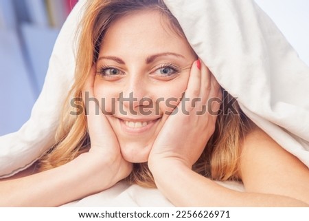 Conceptual image: good happy morning. Young girl lying in bed under the blanket in the morning Horizontal image.