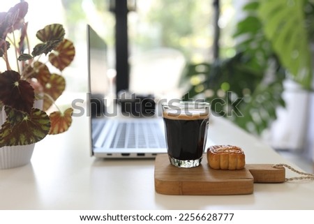 Laptop side view and coffee glass mug and dessert indoor working Royalty-Free Stock Photo #2256628777