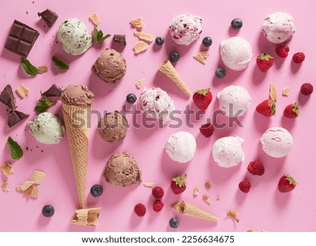 Composition of colorful ice cream scoops with berries and chocolate on pink background with waffle cones arranged together
