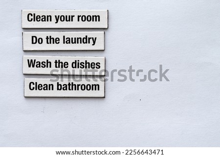 Fridge magnets used to create a list of chores,like "Clean your room, do the laundry, wash the dishes, clean the bathroom", on white background with copy space