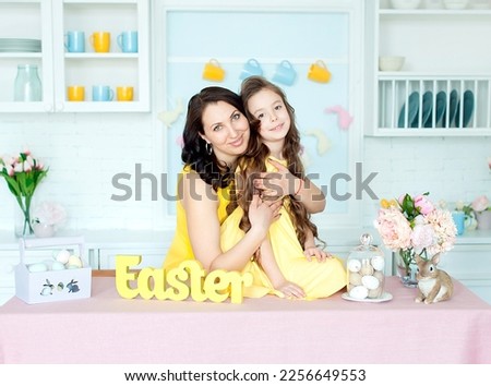 Happy Ester. Mother and daughter together at home Easter celebration sitting looking camera holding basket with eggs