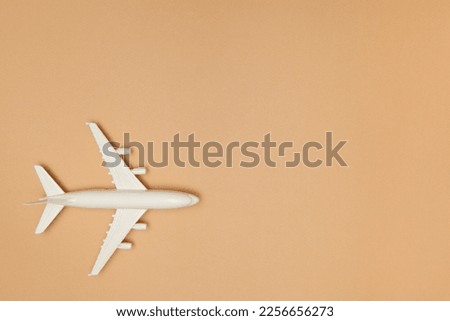 Airplane model. White plane on brown background. Travel vacation concept. Summer background. Flat lay, top view, copy space.