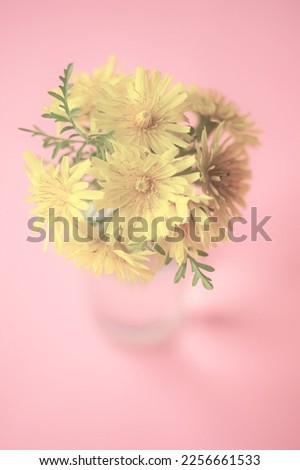 Yellow flowers bouquet on the pale pink table, art card.
