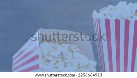 Image of two tubs with red and white stripes of popcorn on grey background. Snacks, cinema and colour concept digitally generated image.